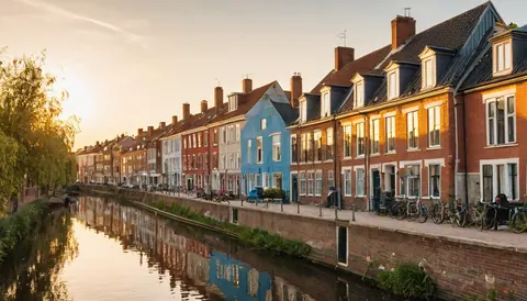 Colorful brick houses line a calm canal with bicycles parked along the quay at sunset.