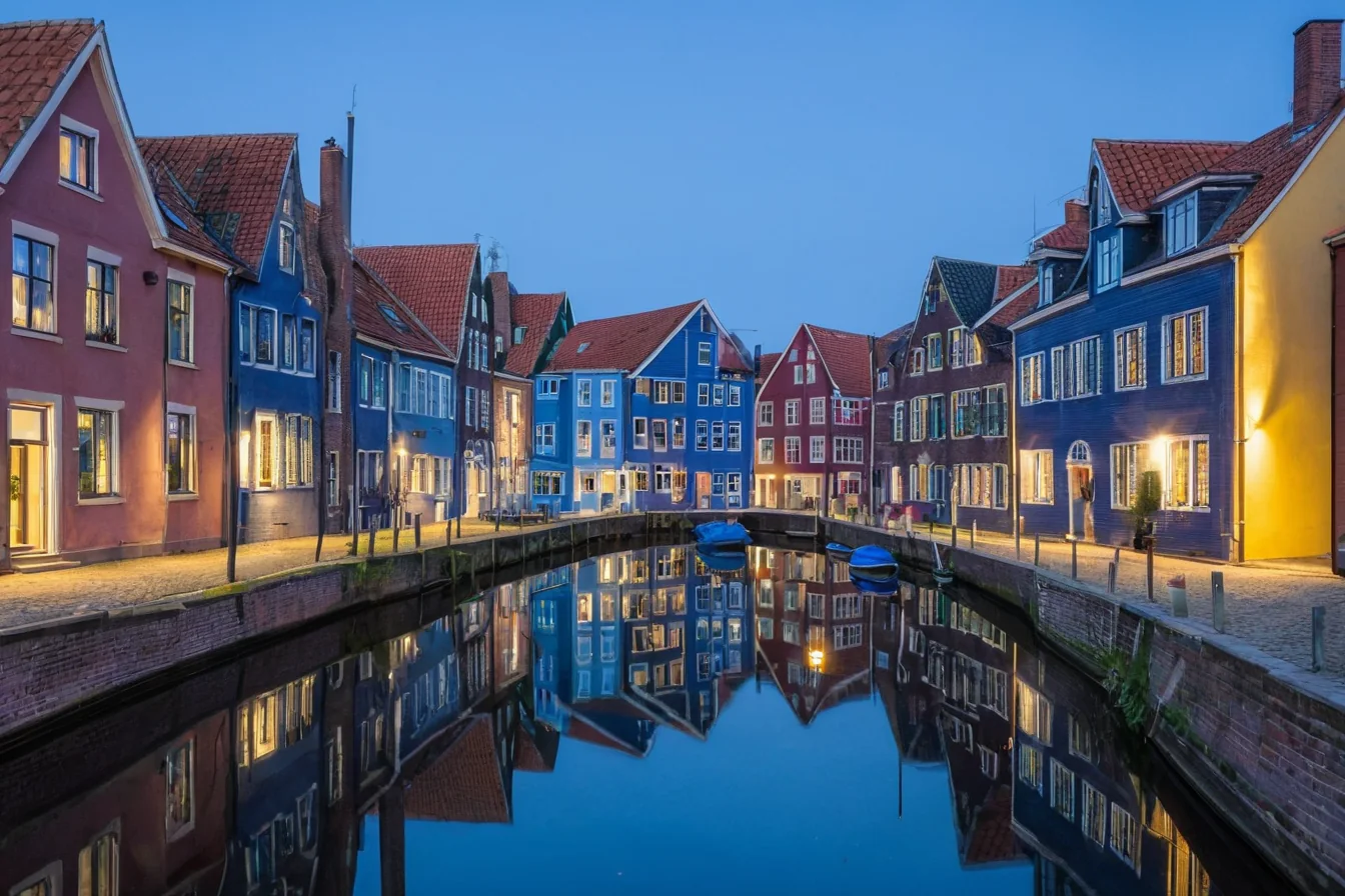 Colorful houses reflected in calm canal water at twilight