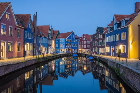 Colorful houses reflected in calm canal water at twilight